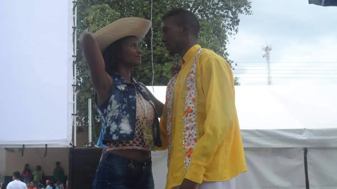 Pareja en vestuario tradicional campesino durante una presentación escénica al aire libre.