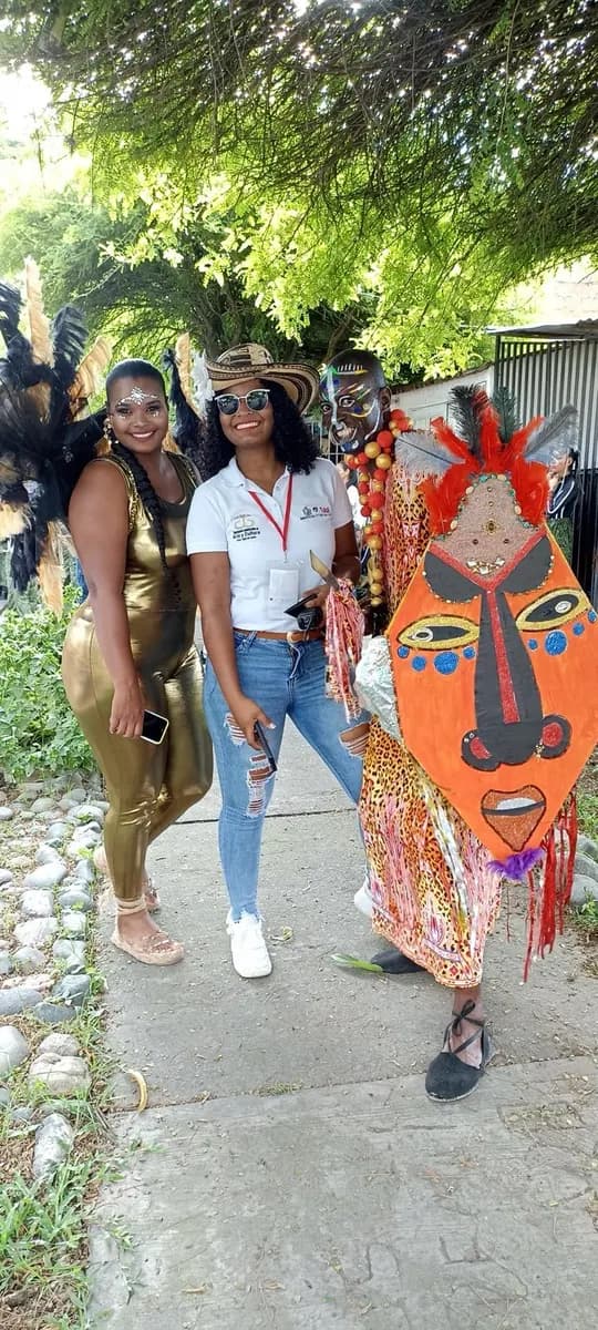 Angie Solís con camisa institucional de Arte y Cultura, escarapela y sombrero vueltiao, acompañando a artistas de comparsa durante un desfile en Tuluá.
