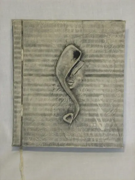 Libreta artesanal encuadernada a mano, con cubierta texturizada en gris y un rostro estilizado en relieve.