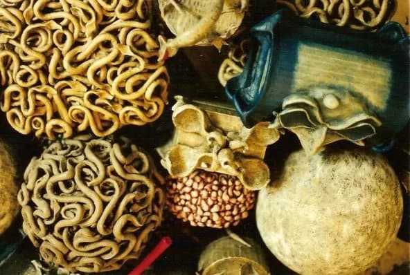 Bodegón de esferas y piezas orgánicas elaboradas con textiles y materiales experimentales en tonos tierra y azul.