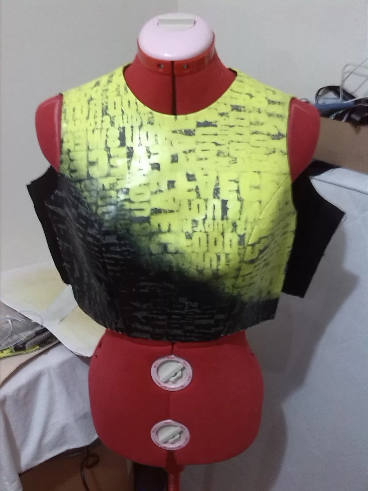 Corpiño en proceso sobre maniquí de costura rojo, con superficie estampada en degradé de amarillo neón a negro.