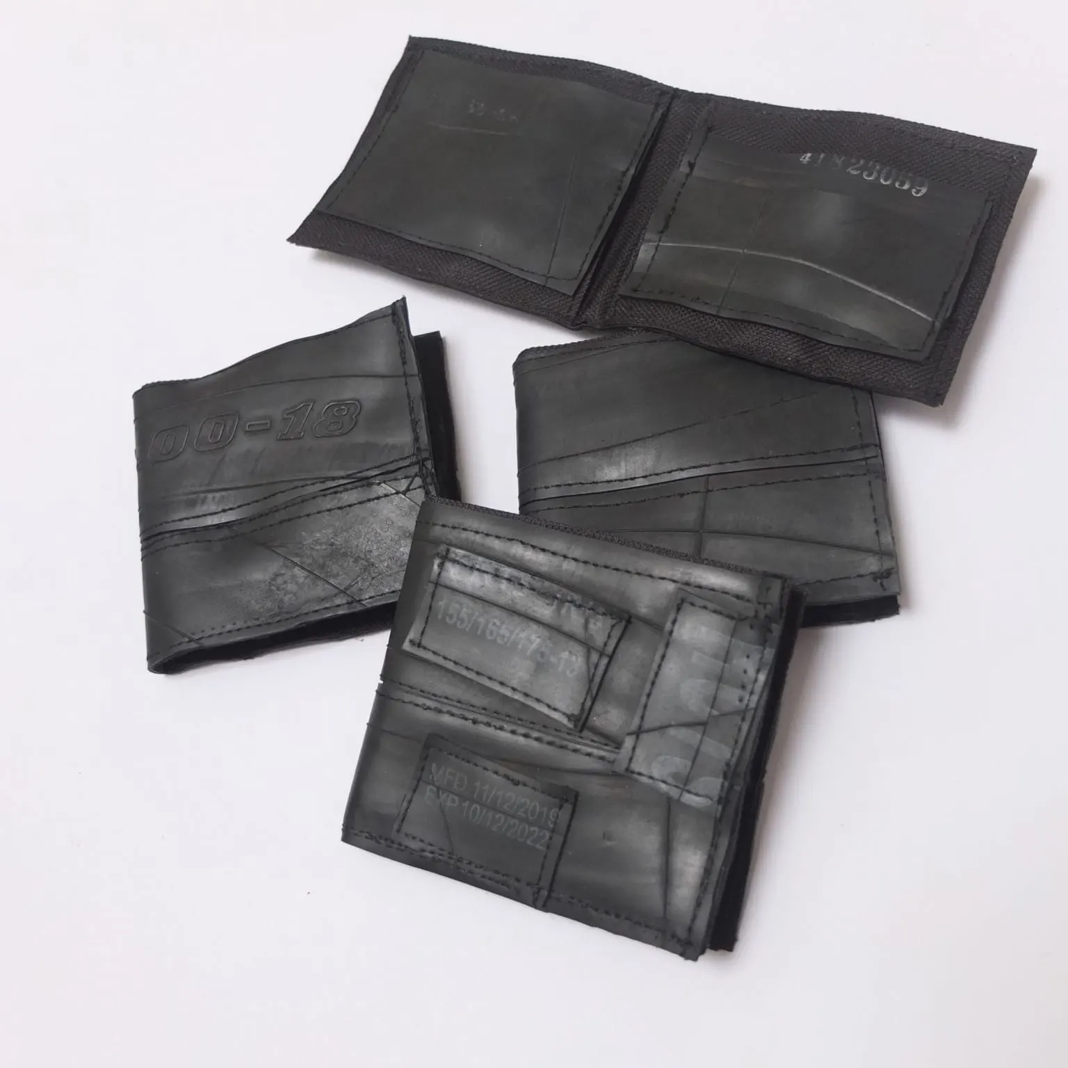 Billeteras elaboradas con caucho de neumático reutilizado, con las marcas y sellos originales de las llantas visibles como parte del diseño.