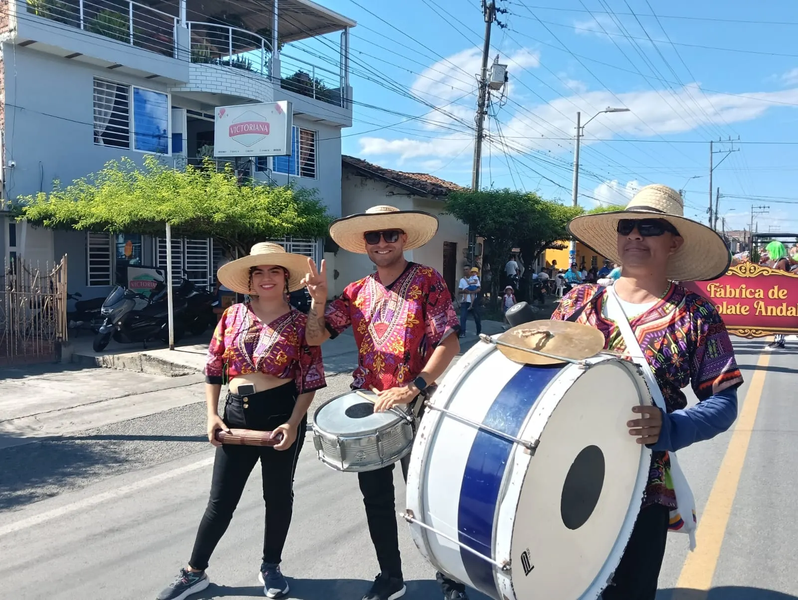 Músicos de comparsa con sombreros de paja, redoblante y tambora desfilan por una calle del municipio durante una fiesta popular.