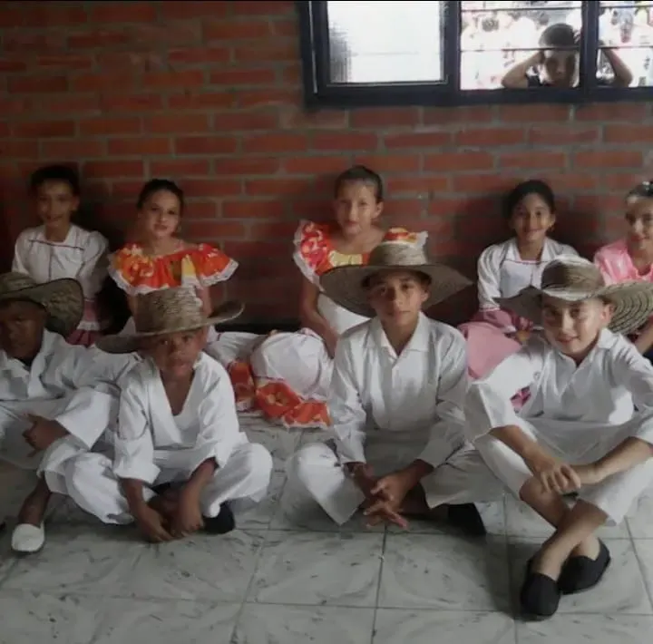 Niños y niñas con trajes típicos de danza tradicional esperan su presentación, muestra de la transmisión intergeneracional del folclor.