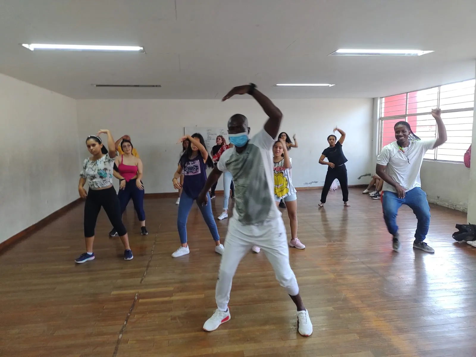 Orlando demuestra una coreografía al frente de un grupo de jóvenes durante una clase en un salón de ensayo.