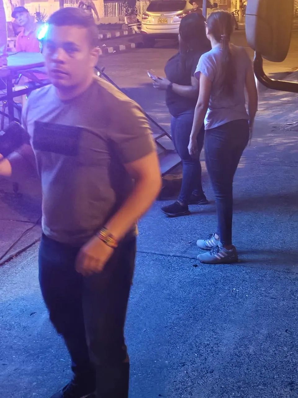 El gestor en primer plano durante una actividad nocturna en el espacio público, con asistentes y luces de evento al fondo.